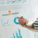 Tangan menunjuk grafik keuangan dalam rapat analisis laporan keuangan perusahaan