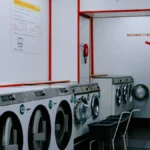 Deretan mesin cuci di dalam laundromat modern, menggambarkan berbagai pilihan mesin cuci kapasitas besar